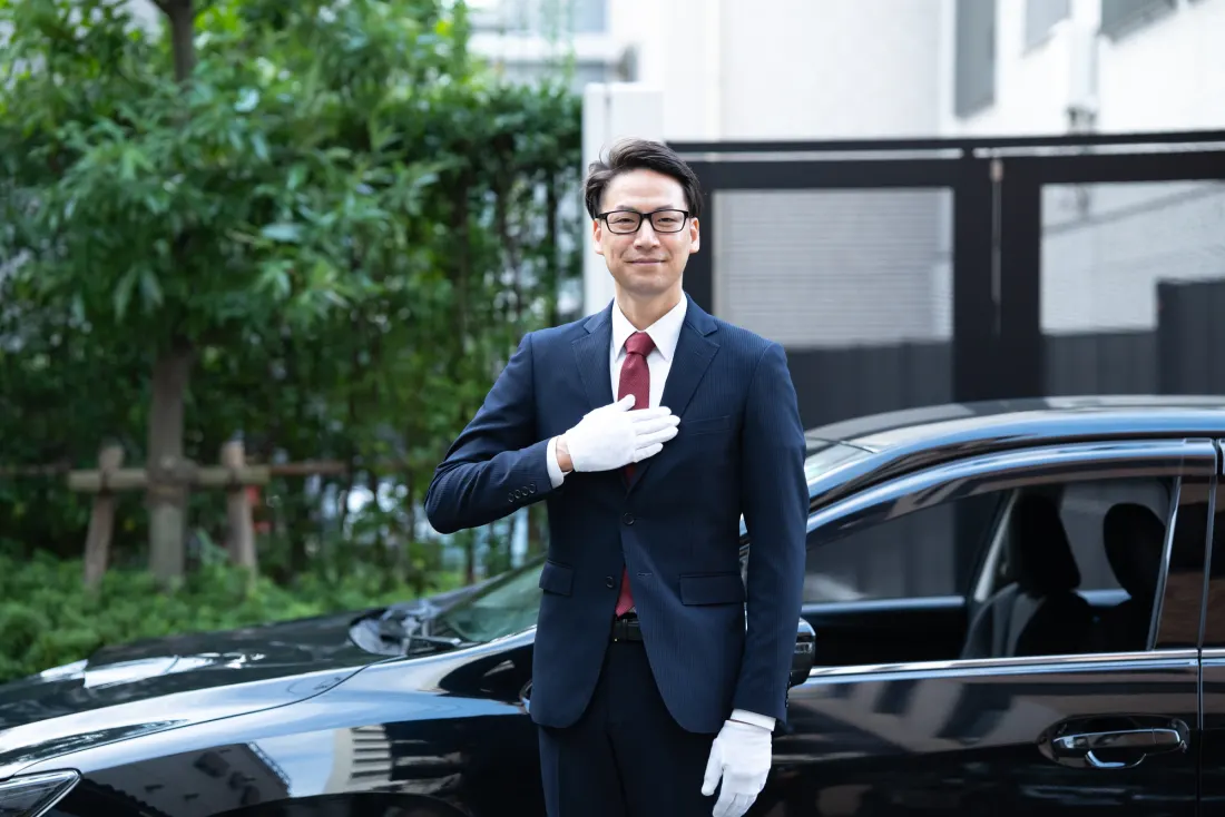 ハイヤーの前でお客様をお迎えするドライバー